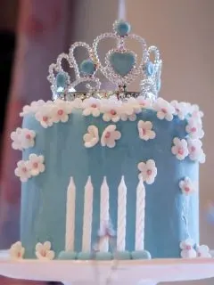 blue cake with white sugar flowers and a crown