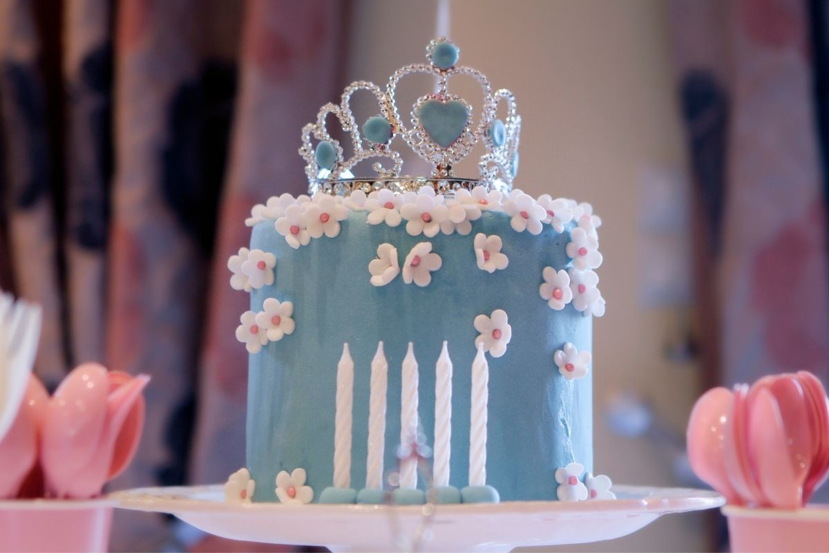 blue cake with white sugar flowers and a crown