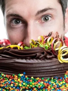young man with his face burried into a choclolate cake