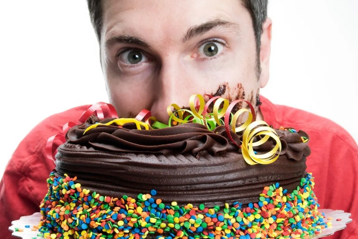 young man with his face burried into a choclolate cake