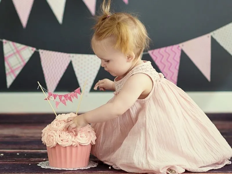 cute one year old girl checking out her smash cake