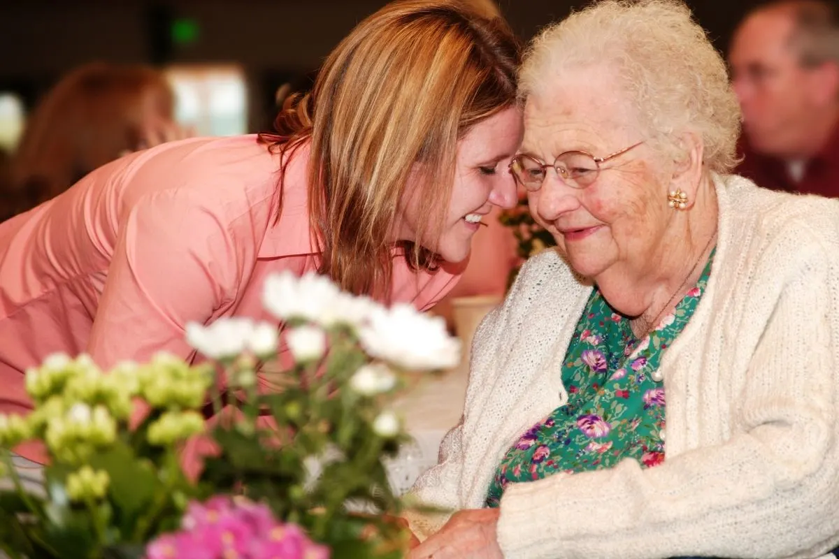 older woman in wheelchair receiving flowers