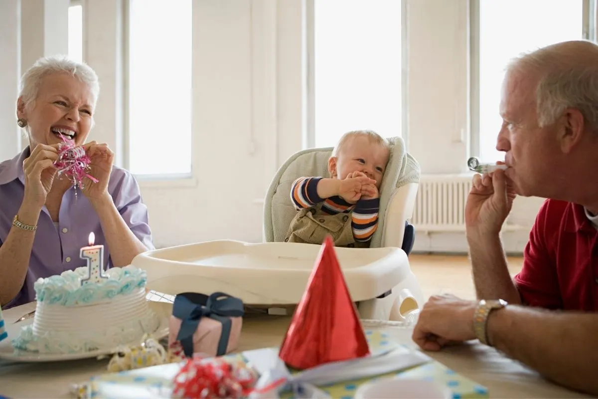 boy celebrating first birthday with grandma and grandpa